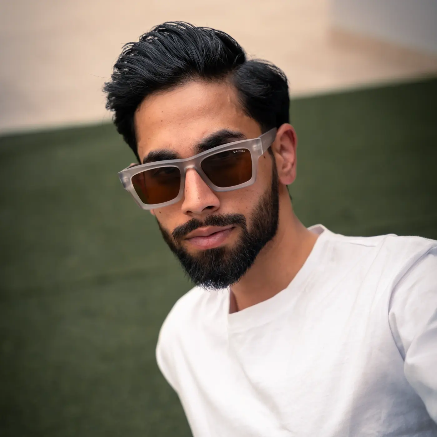 Bearded man in a white tee wearing clear-frame sunglasses